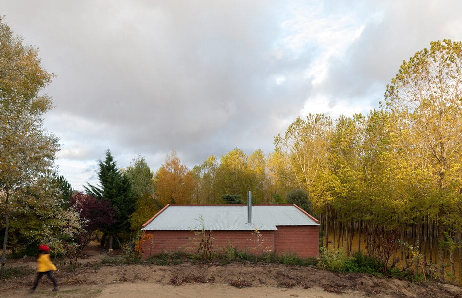 Refugio integrado en el paisaje, al fondo se observa una chopera en otoño.