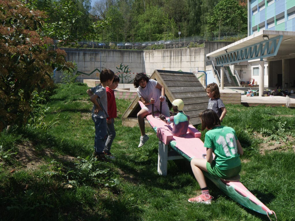 Niños jugando juegos de equilibrio entorno verde.